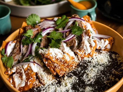 Chilaquiles en totopos crocantes con crema, queso Cotija, cebolla morada, cilantro y aguacate