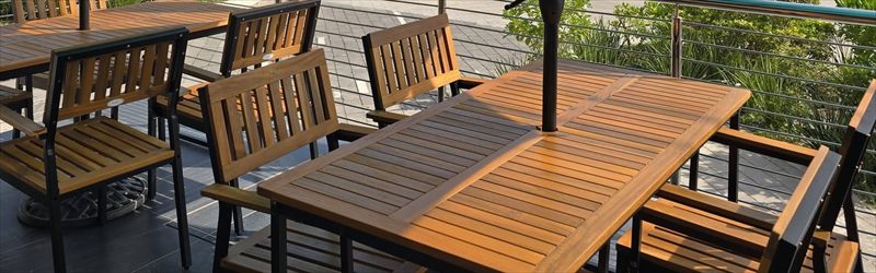 Terraza de Cafferium Torre Central con mesas y sillas de madera, barandal metálico y plantas