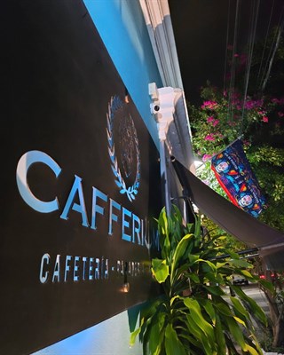 Letrero de Cafferium entre plantas y buganvilla
