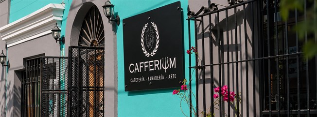 Fachada turquesa de Cafferium Centro Histórico con rejas de hierro forjado y el letrero de la casa